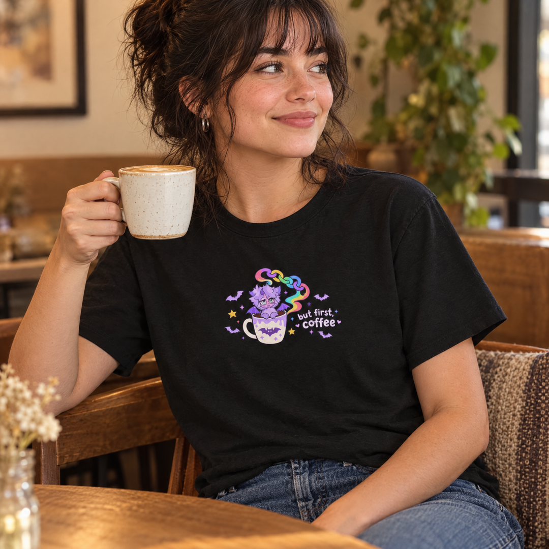 Woman in the But First, Coffee Tee holding a coffee in a cafe
