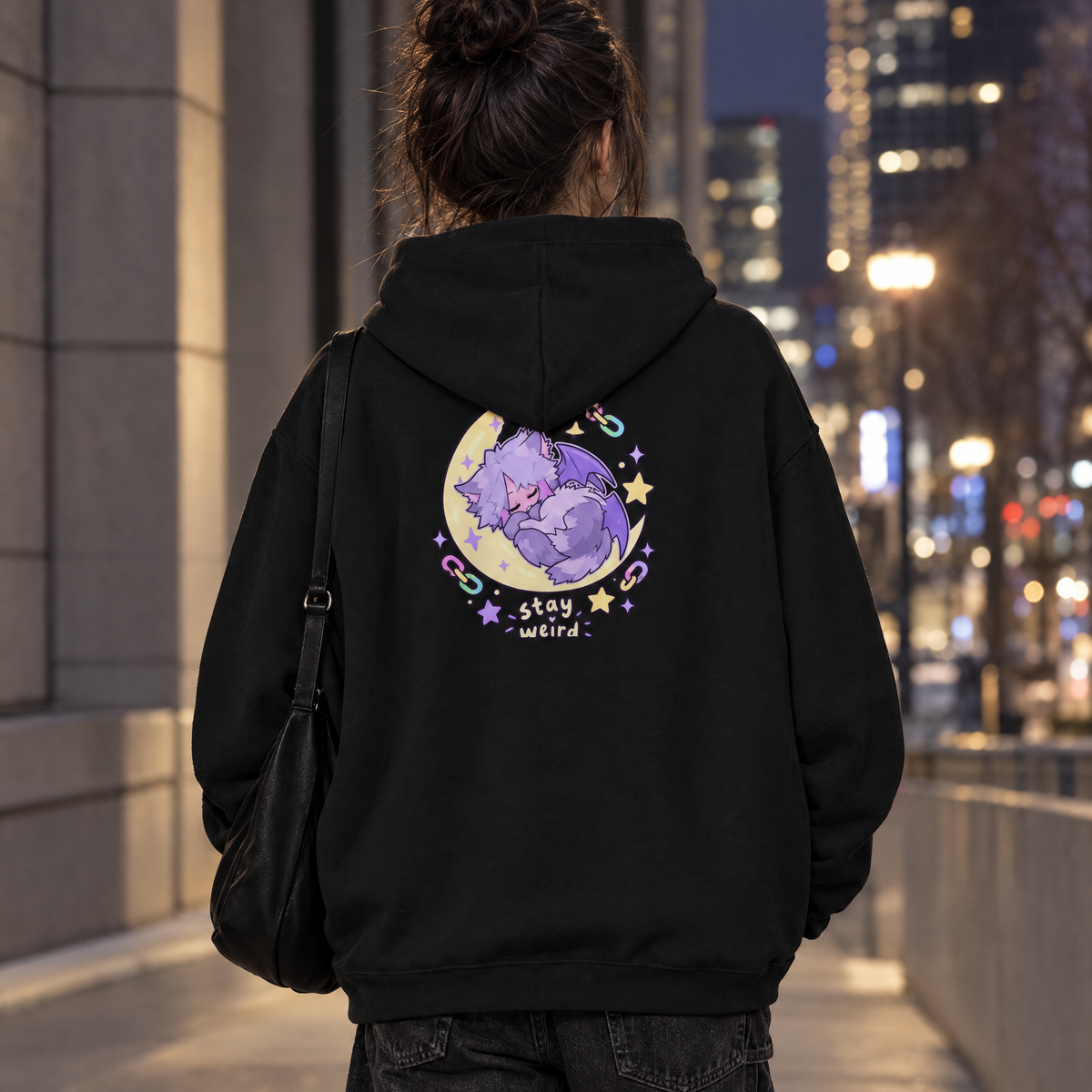 Person wearing the Stay Weird Hoodie with the sleepy bat-kitten moon back print